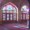 نمای پانورامای مسجد نصیرالملک (مسجد صورتی) نور خورشید صبحگاهی از میان شیشههای رنگی روی ستونها، دیوار و کف منعکس میشود.