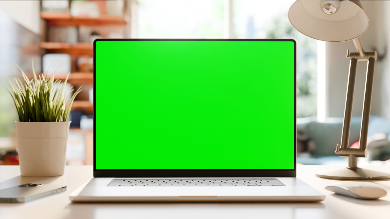 فوتیج یک نمای ثابت از یک لپتاپ با صفحه نمایش سبز روی میز در یک دفتر کار خانگی. درختانی که در باد تکان میخورند از بیرون پنجره قابل مشاهده هستند. فیلم تکرار شده. رندر سه بعدی، ویدیوی استوک