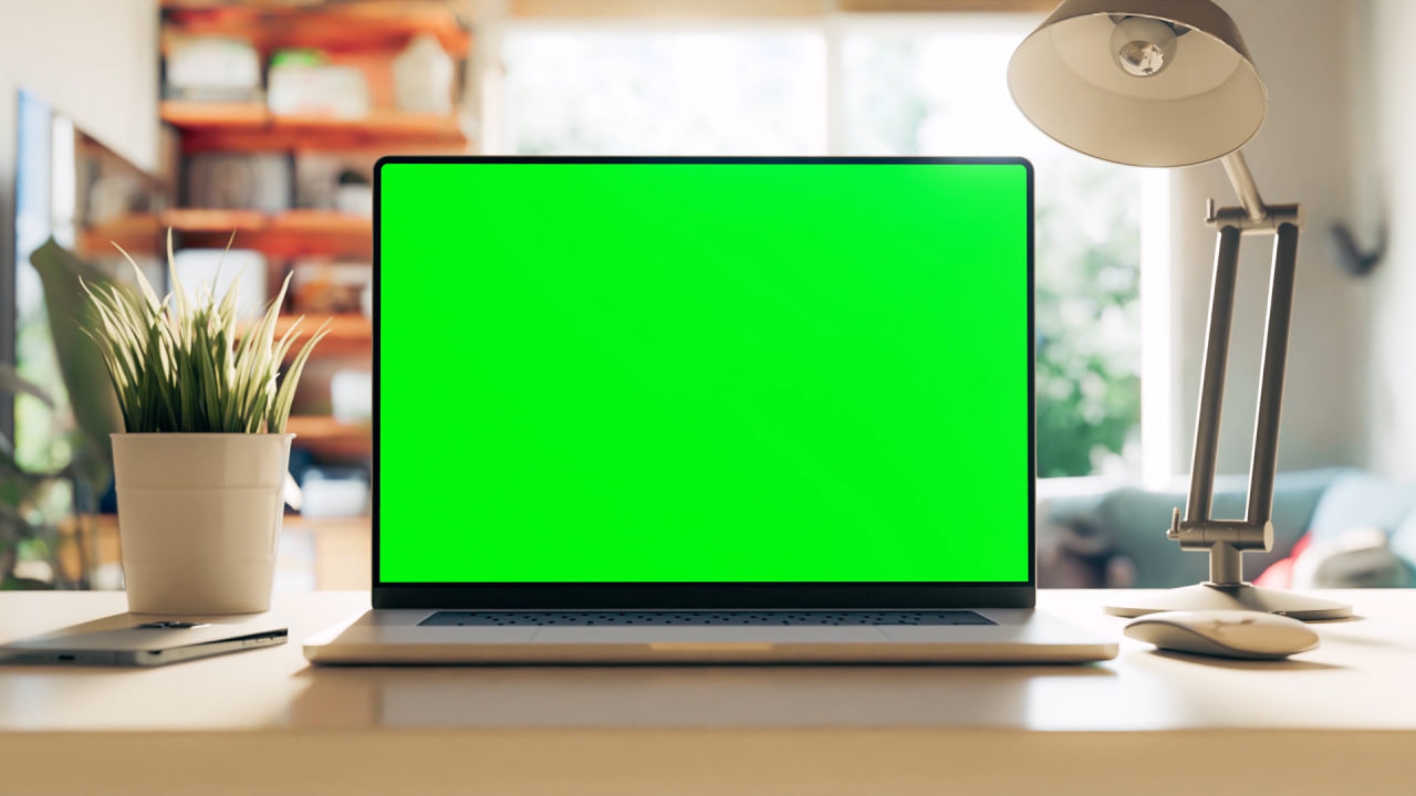 یک لپتاپ با صفحه نمایش سبز روی میز یک دفتر کار خانگی دنج و روشن قرار دارد. مجموعه ۵ صحنه. این فیلم شامل یک لایه ردیابی است. ویدیوی استوک