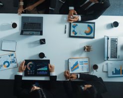 نمای هوایی از بالا به پایین از مدیر در حال ایستادن و ارائه طرح کسب و کار به سرمایه گذار ماهر. تیم تجاری با هم برای تجزیه و تحلیل نمودار آمار مالی در میز جلسه همکاری می‌کنند. تایم لپس. دپارتمان.