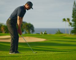 مردی در زمین گلف لوکس و زیبای تفریحی گلف بازی می‌کند، در حال تاب دادن و ضربه زدن به توپ گلف در حرکت آهسته