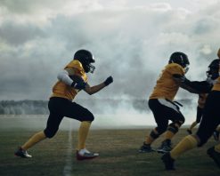 زمین فوتبال آمریکایی، بازی دو تیم: بازیکن موفق از روی خط دفاعی می‌پرد و برای کسب امتیاز تاچ‌داون می‌دود. ورزشکاران حرفه‌ای برای توپ رقابت می‌کنند و برای پیروزی می‌جنگند. ویدیوی استوک صحنه آهسته دراماتیک با کیفیت 4K