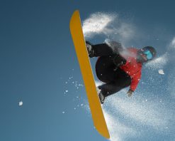 ویدیوی استوک حرکت آهسته از نمای نزدیک: اسنوبردسوار در حال پریدن و پرواز بر فراز خورشید در آسمان آبی صاف با کیفیت HD